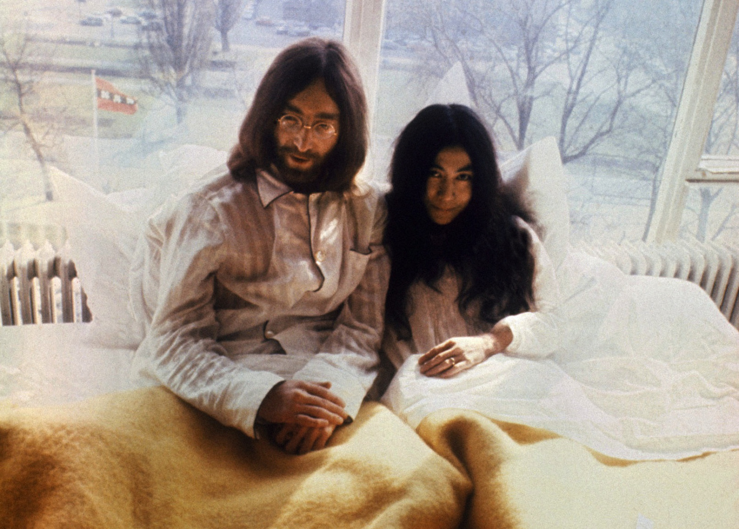 US musician John Lennon (R) and his japanese wife Yoko Ono (L) pose for photographers in Amsterdam 27 March 1969. The honeymoon couple is spending a week in bed at Hilton Hotel to protest against world violence. (FILM) AFP PHOTO (Photo credit should read -/AFP/Getty Images)